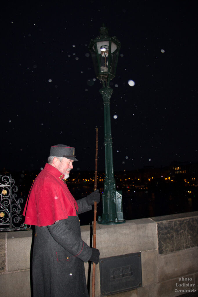 Advent v Praze - Lampář rozsvěcí plynové lampy na Karlově mostě