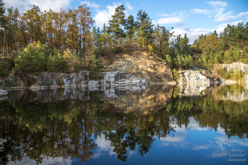 Zatopený žulový lom zrcadlí podzimní les