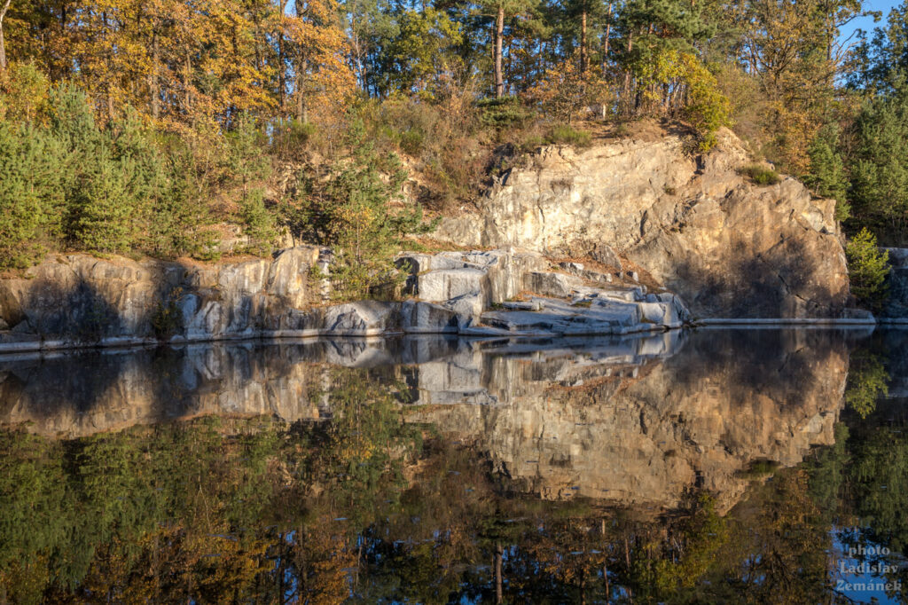 Zatopený žulový lom zrcadlí podzimní les