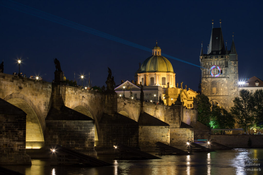 Karlův most s laserovou instalací ke Dni světla - Staroměstská mostecká věž a Kostel sv. Františka z Assisi