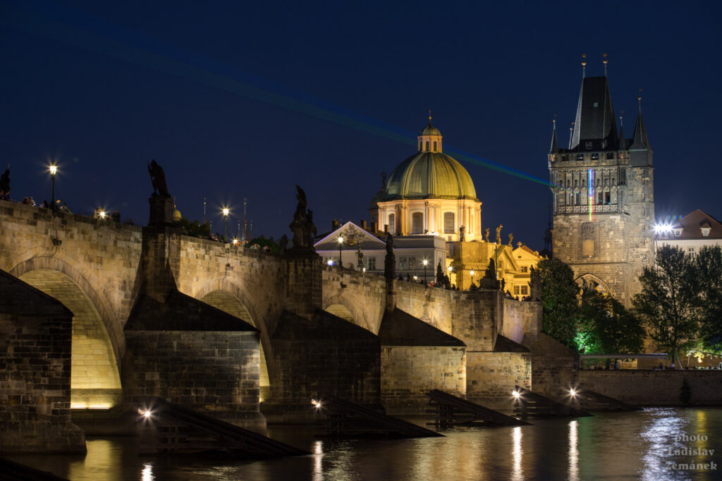 Karlův most s laserovou instalací ke Dni světla - Staroměstská mostecká věž a Kostel sv. Františka z Assisi